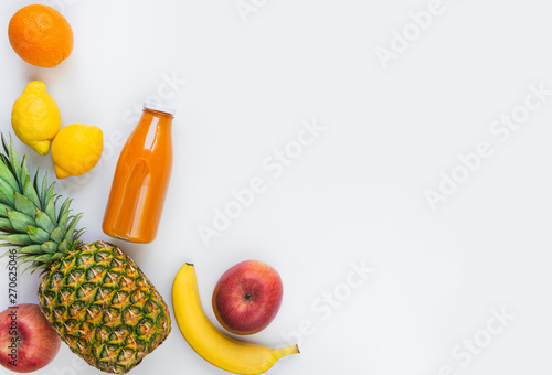 Top view of various fruits and a bottle of freshly squeezed  multivitamin juice on a white background. Copy space. Flat lay.