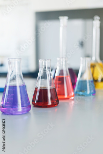 Chemical laboratory flask with blue purple-pink liquid stand on the table