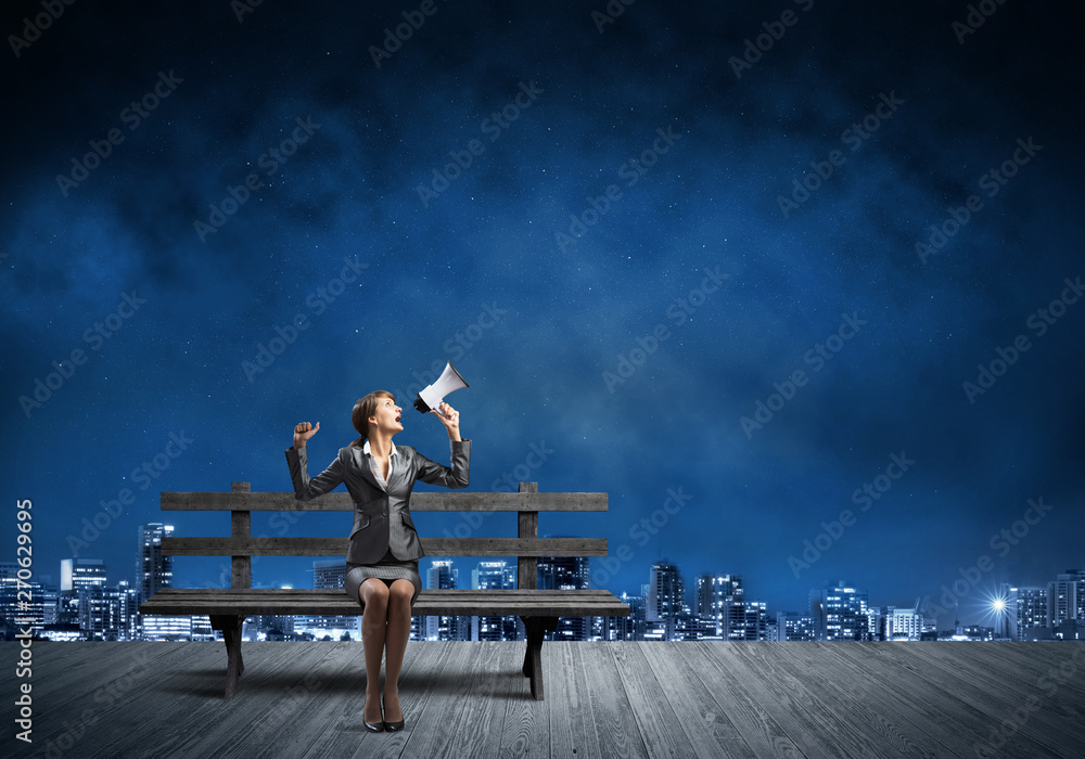 Business woman with megaphone on wooden bench