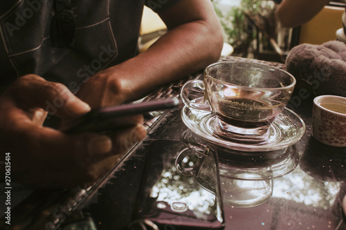 The young man checks the phone after drinking a cup of coffee.