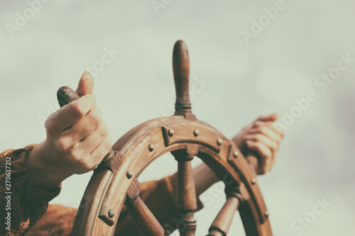 Steering hand wheel ship on sky background, hand hold hand wheel photo