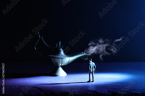 Concept picture of a businessman looking at Aladdin lamp with smoke, asking for a wish
