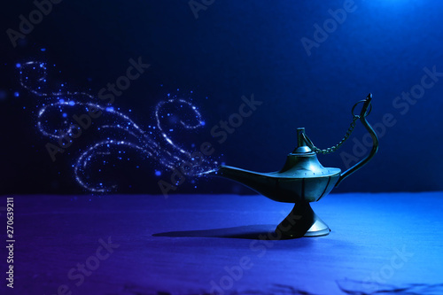 Image of magical mysterious aladdin lamp with glitter smoke. Dark background and dramatic light photo