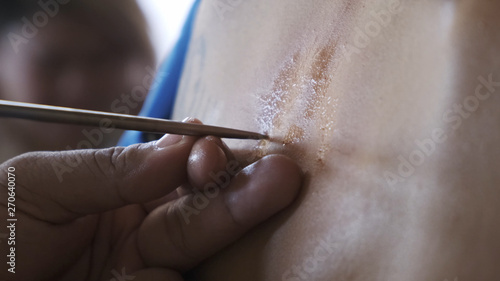 yantra tattoo or sak yant, thai sacred tattoo. master draws a girl colorless tattoo Sak Yant with a special oil. Thailand.