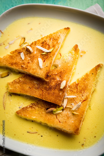 shahi tukra/tukda or Double ka meetha is a bread pudding Indian sweet of fried bread slices soaked in rabid or sweet saffron milk garnished with dry fruits, selective focus photo