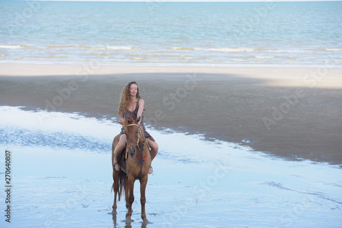 Portraits of beautiful women riding horses happily at the beach by the sea