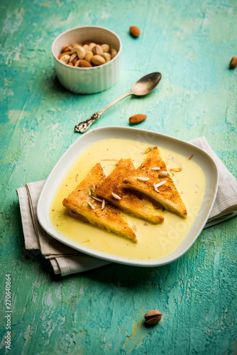 shahi tukra/tukda or Double ka meetha is a bread pudding Indian sweet of fried bread slices soaked in rabid or sweet saffron milk garnished with dry fruits, selective focus photo