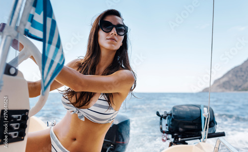 Beautiful woman in bikini sailing a motorboat