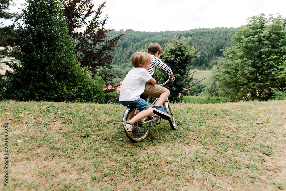 boy holding on tightly to boy in front of bike boy holding on tightly to boy in front of bike