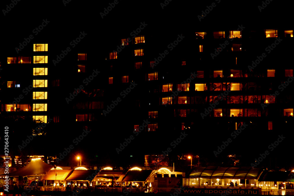 bright light in the square windows of a multistory building at night in the city