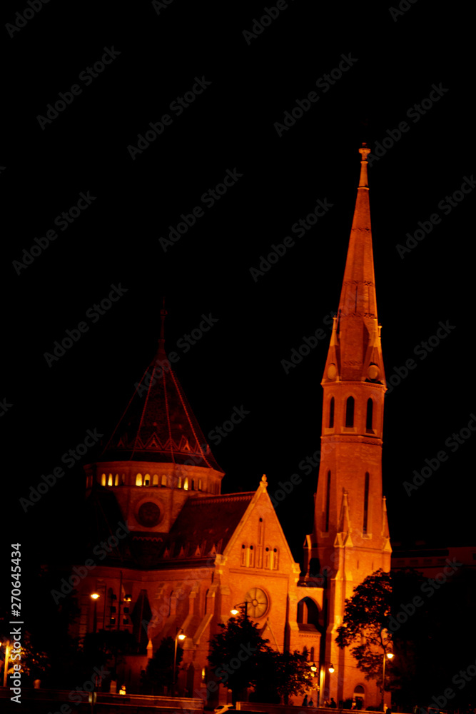 the high-spire building on the roof glows yellow at night. night city. high chapel
