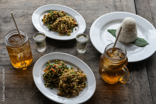 traditional Balinese food called lawar. Lawar is minced meat mixed with vegetables, long beans and spices then stirred evenly. Eat using rice and freash iced tea. Served on a wooden table