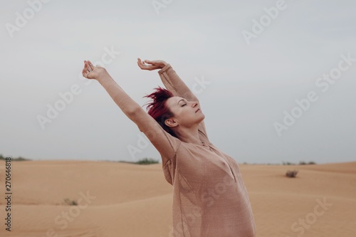 Young redhead woman enjoying wind in desert photo