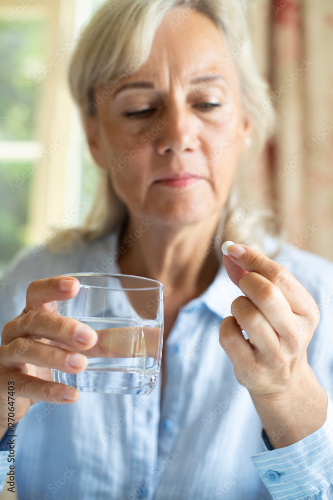 Senior Woman Taking Tablet With Glass Of Water At Home Senior Woman Taking Tablet With Glass Of Water At Home