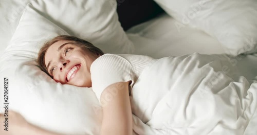 Happy smiling woman lovely stretching and hugs pillow in bed in sunny morning