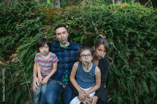 Family of four together outside in ferns goofing around photo