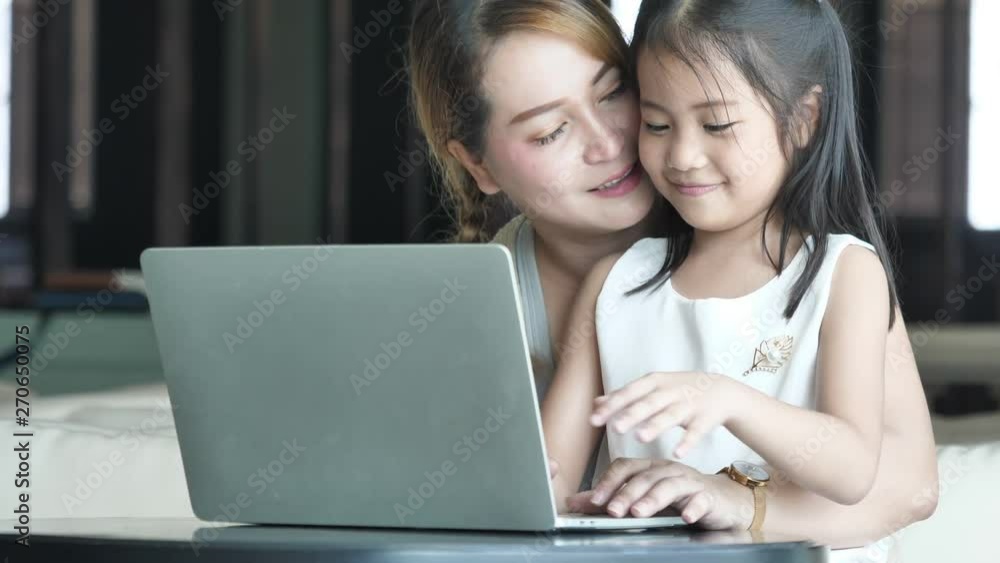 Asian mother using laptop with little girl Asian mother using laptop with little girl