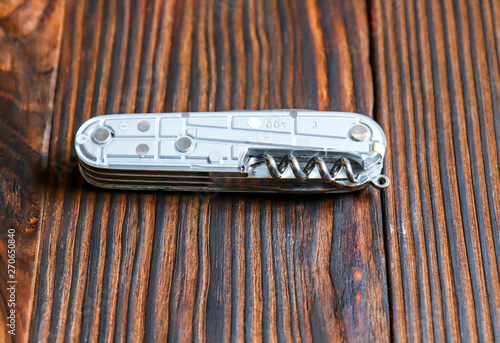 Obraz na plátne Multifunctional knife in folded form on a wooden background close up