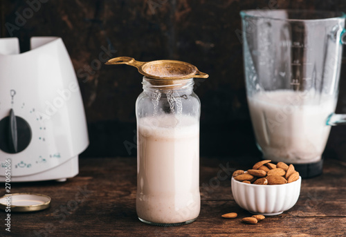 Food: Almond milk in a bottle with some almonds besides and blen photo