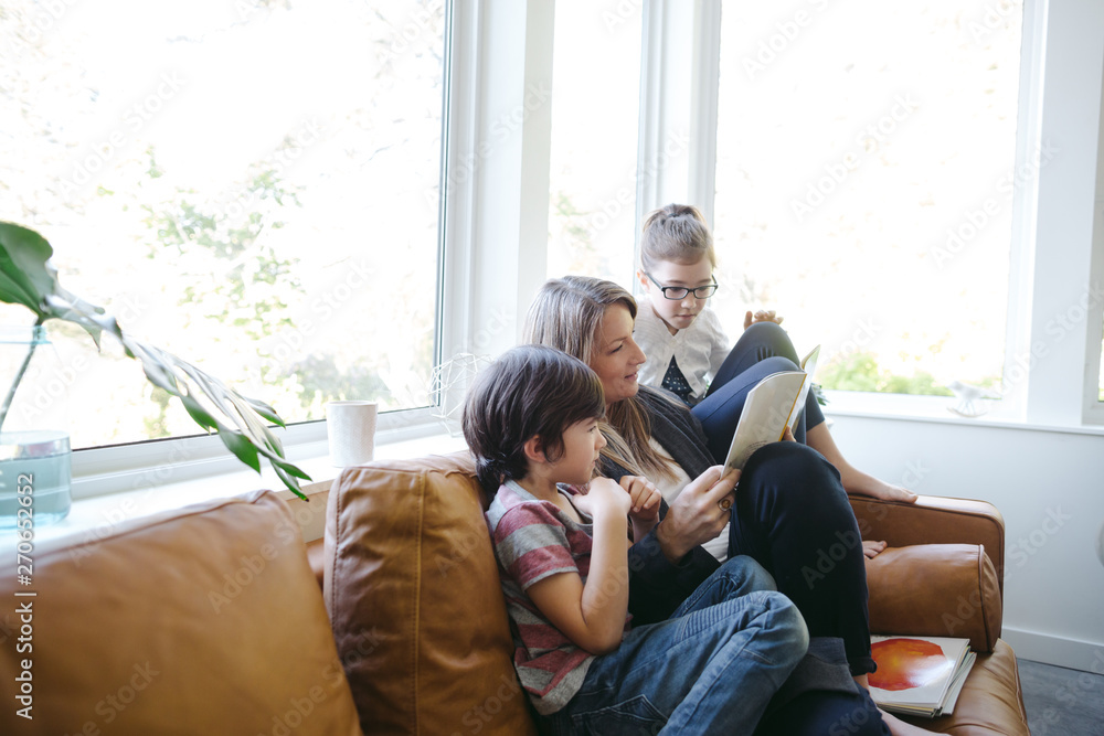 Mom reading book to kids at home on the couch Mom reading book to kids at home on the couch