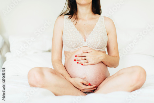indistinguishable woman with hands put on her pregnant tummy