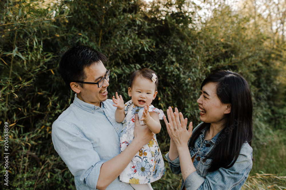 Happy Asian Family Snuggling, Cuddling and being Playful Outdoors Happy Asian Family Snuggling, Cuddling and being Playful Outdoors