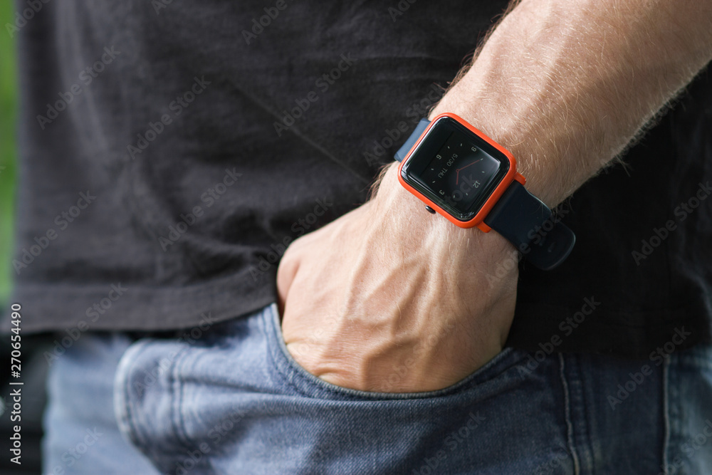 Image of man putting his hand in his jeans pants pocket, wearing a smart  watch. Technology. Trees on background. Photos | Adobe Stock