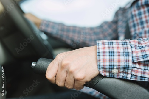 Men use hands to pull the handbrake lever in the car