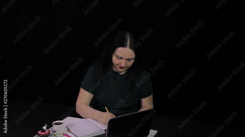 A pensive woman at a table in a cafe works at a computer and drinks coffee A pensive woman at a table in a cafe works at a computer and drinks coffee