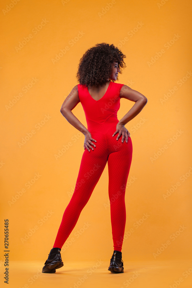 Back of strong athletic woman with black skin and curly hair, doing exercise on white background wearing red sportswear. Fitness and sport motivation. Back of strong athletic woman with black skin and curly hair, doing exercise on white background wearing red sportswear. Fitness and sport motivation.