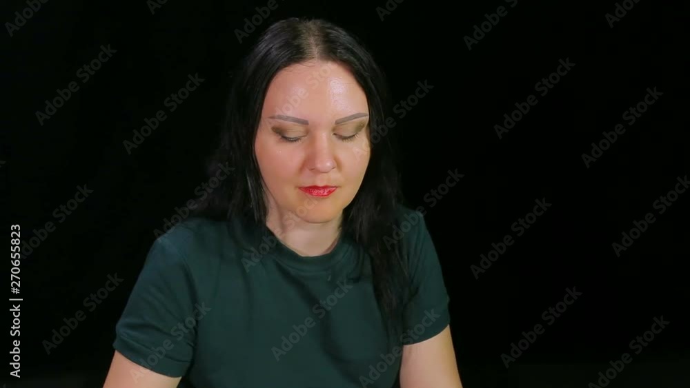 A brunette woman on a black background is drinking coffee and eating a cake A brunette woman on a black background is drinking coffee and eating a cake