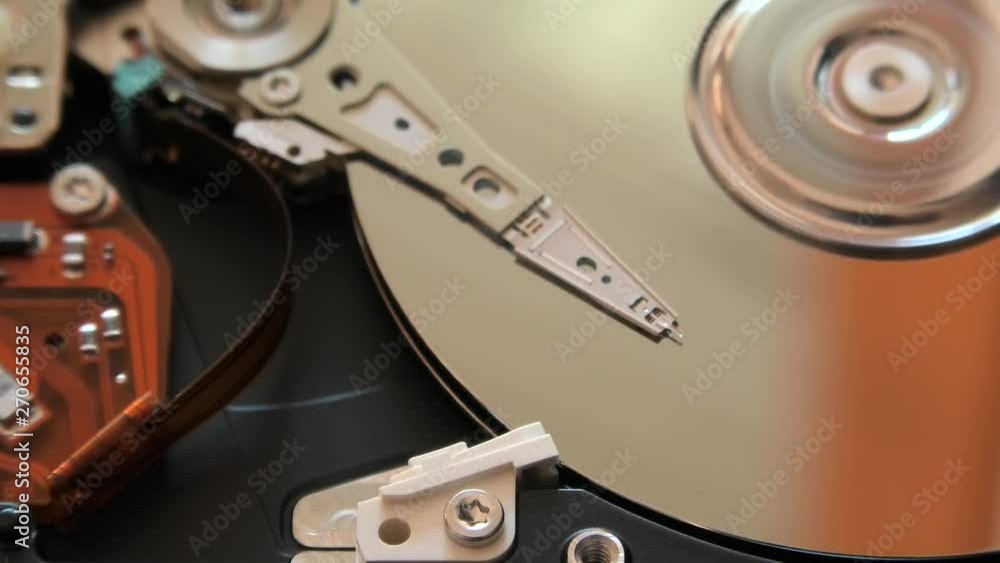 close up of interior of an hard disk drive writing data on the support with its head. close up of interior of an hard disk drive writing data on the support with its head.