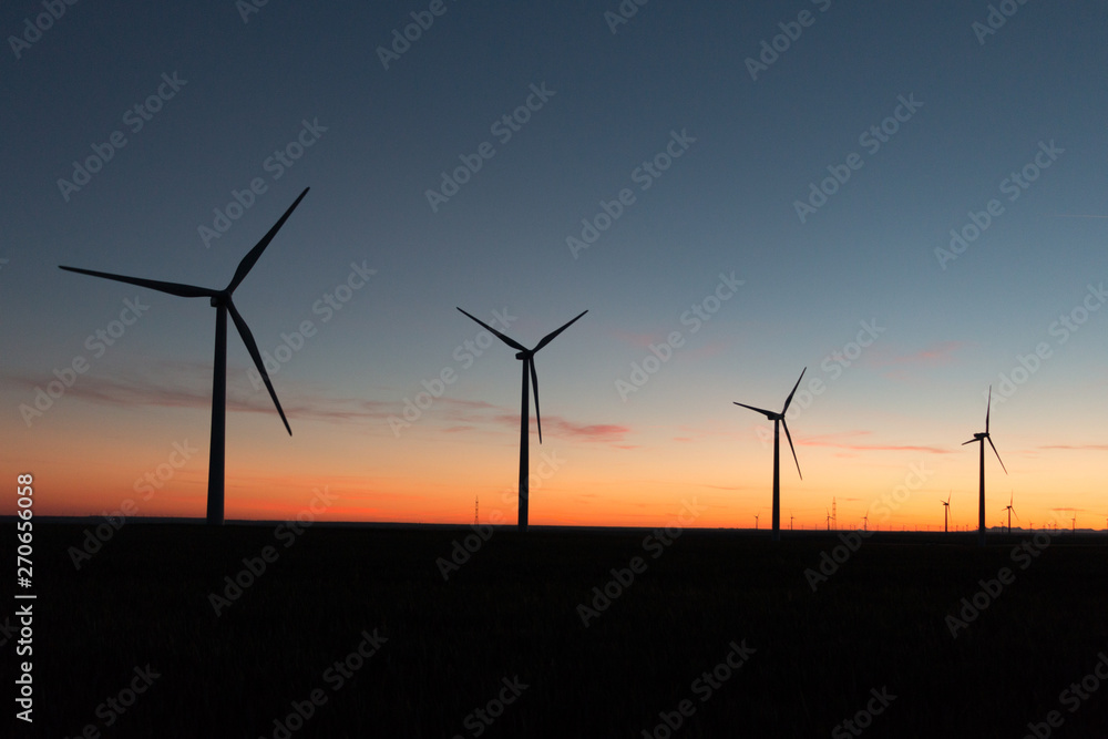 A landscape with windmills in a wind farm at sunset. A landscape with windmills in a wind farm at sunset.