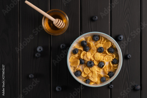 Breakfast. Healthy food - cornflakes with berry and honey on black table. Kitchen. Vegetarian delicious meal