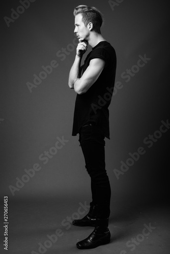 Studio shot of young handsome man against gray background in bla © Ranta Images