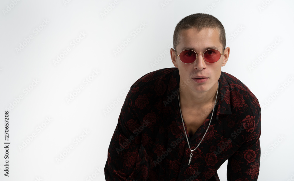 Obraz premium Half length portrait of cheerful sexy man in red sun glasses, wearing trendy black shirt, looking at the camera, isolated over white background