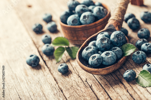 Blueberries in wooden spoon on old wood table. Healthy eating and nutrition concept.