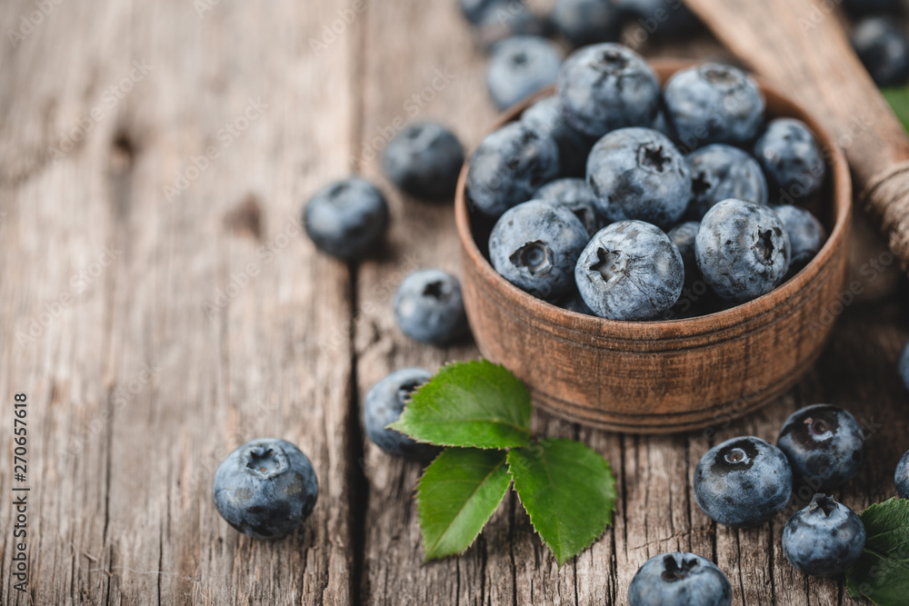 Freshly picked blueberries in wooden bowl on wooden background. Healthy eating and nutrition. Freshly picked blueberries in wooden bowl on wooden background. Healthy eating and nutrition.
