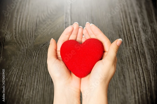 Hands of young woman holding red heart