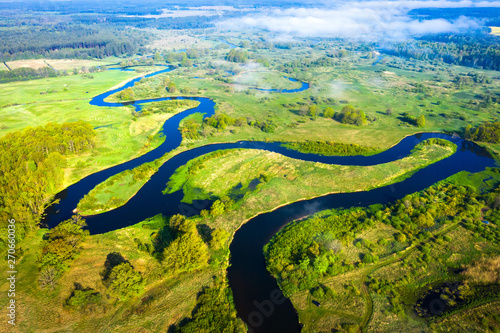 Obraz na płótnie Aerial view on summer river. River stream on green meadow. Summer nature landscape. Drone view on riverside. w salonie