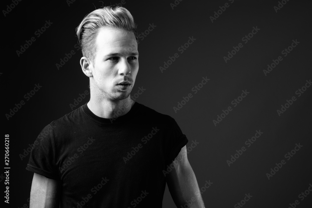 Studio shot of young handsome man against gray background in bla