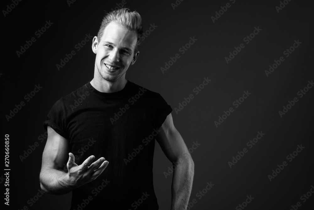 Studio shot of young handsome man against gray background in bla