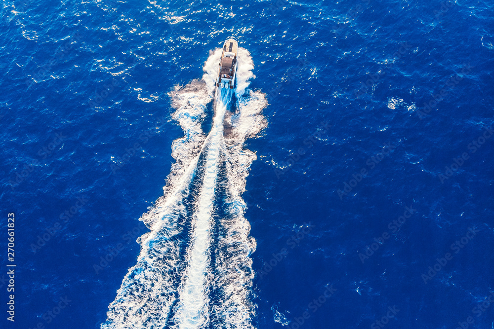 Luxury private speed motor boat leaving blue sea. Aerial top view