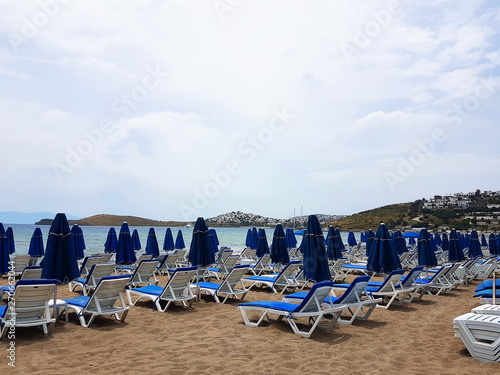 Lots of blue sunbeds with umbrellas at the sea beach