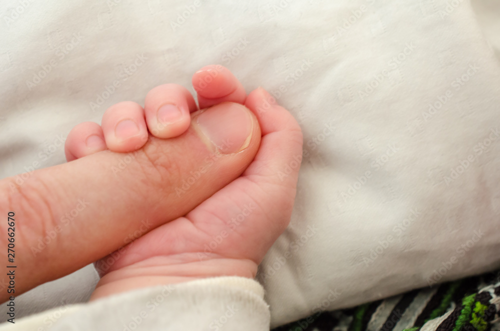 Hand of newborn baby holding male adults finger. Concept of help and family. Father holding hand. Hand of newborn baby holding male adults finger. Concept of help and family. Father holding hand.
