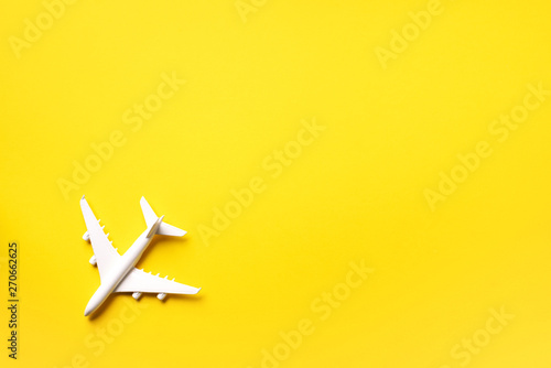 Creative layout. Top view of white model plane, airplane toy on yellow background. Flat lay with copy space. Summer trip or travel concept