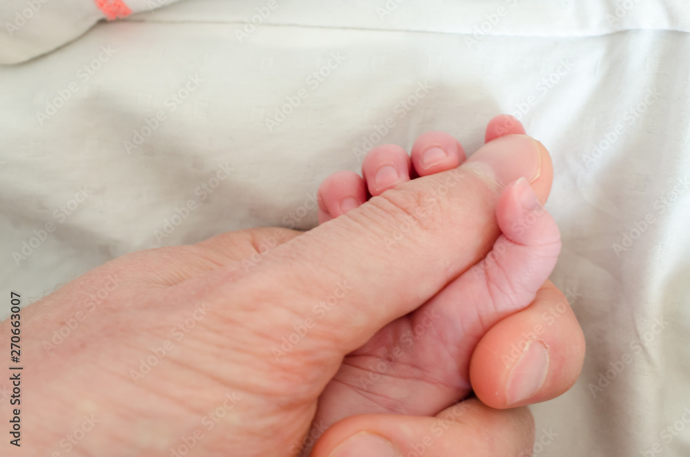Hand of newborn baby holding male adults finger. Concept of help and family. Father holding hand. Hand of newborn baby holding male adults finger. Concept of help and family. Father holding hand.