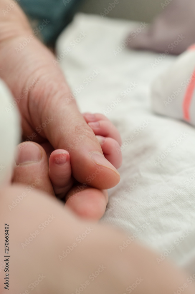 Hand of newborn baby holding male adults finger. Concept of help and family. Father holding hand.