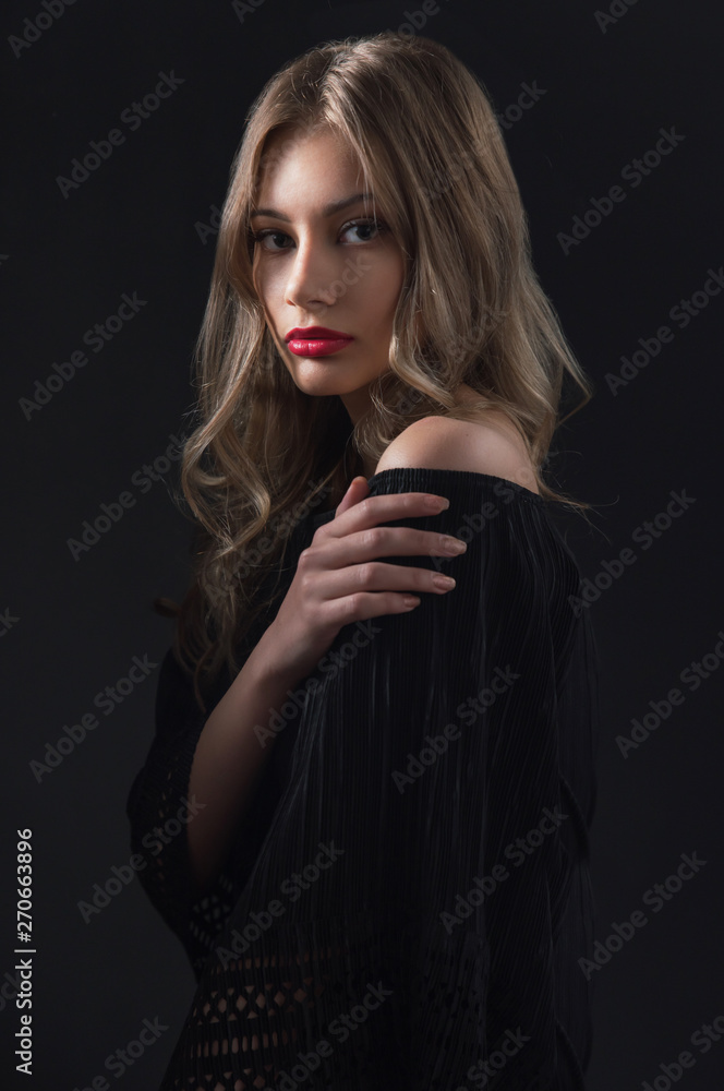 Fototapeta premium Beautiful ,young blonde with bright red lips and expressive eyes in a black jumpsuit. Beauty portrait of a girl. Emotional and bright appearance. Fashion portrait of a woman.