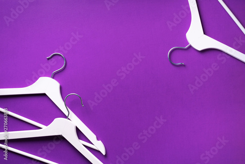 Top view of white clothes hangers on violet background with copy space. Flat lay. Minimalism style. Creative layout. Fashion, store sale, shopping concept. Banner for feminine blog photo